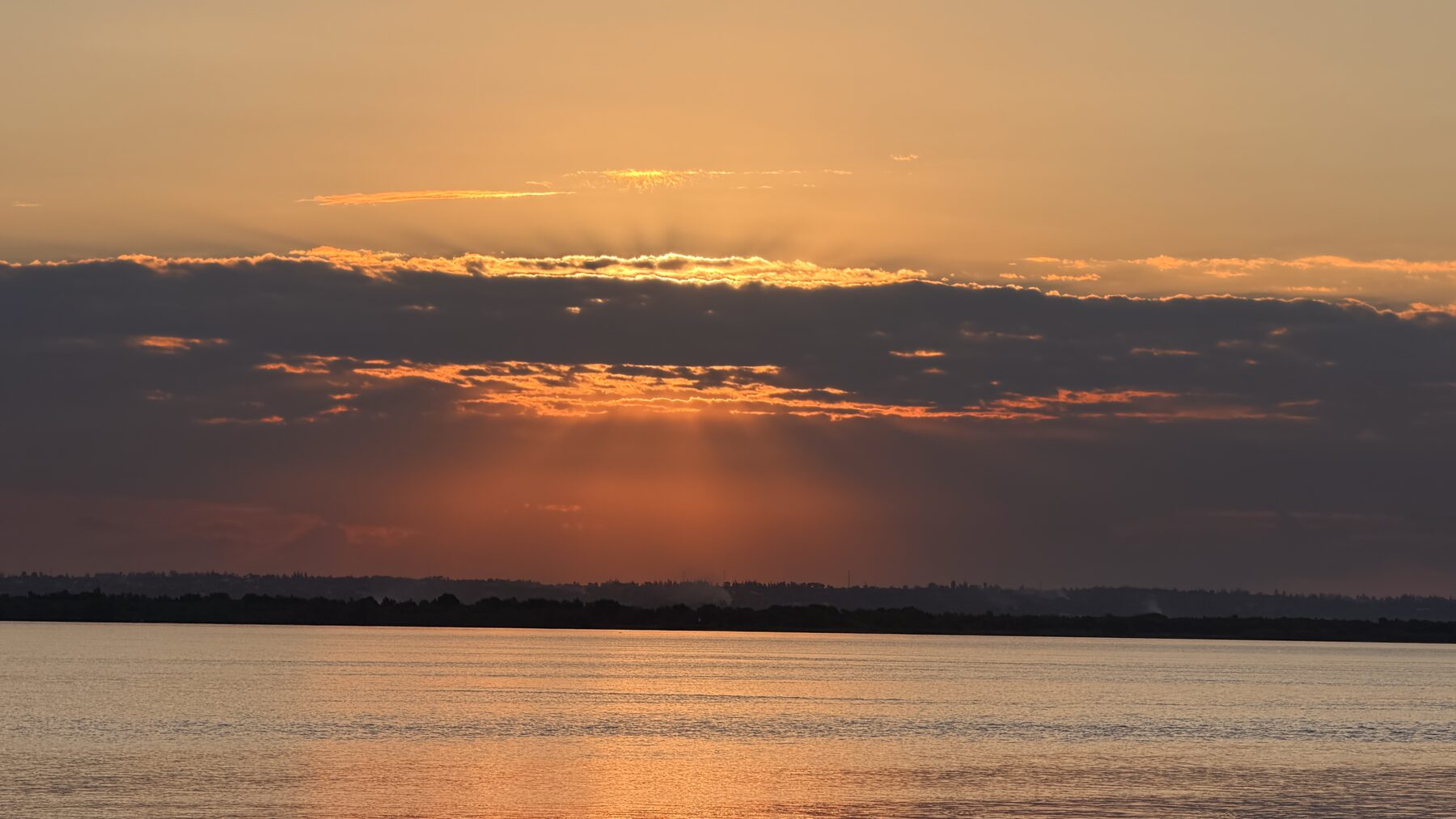 Pôr do sol sobre o rio Incomáti, com raios de luz entre as nuvens